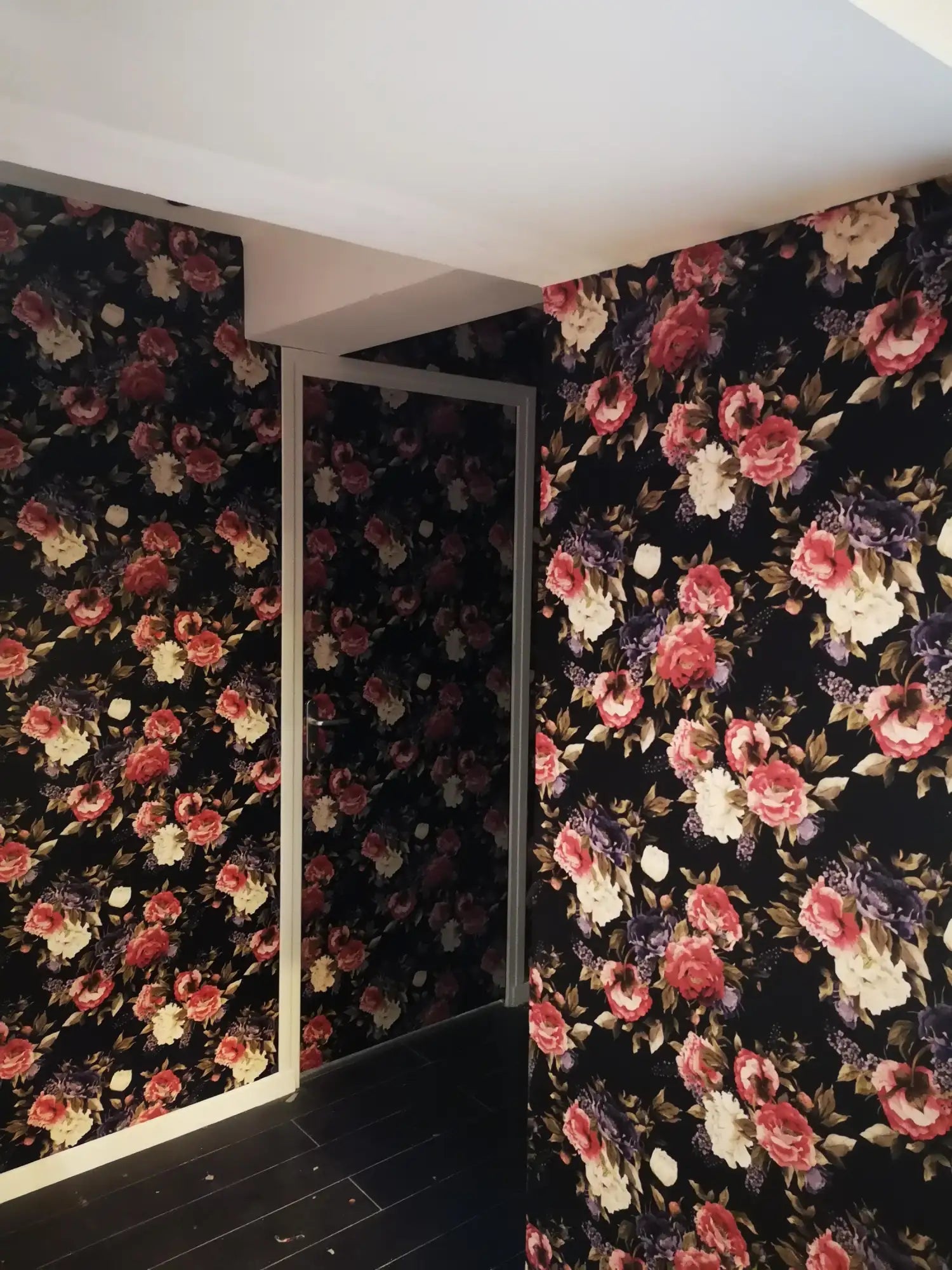 Papier peint floral avec fond noir et fleurs vives rouges, roses, blanches.
