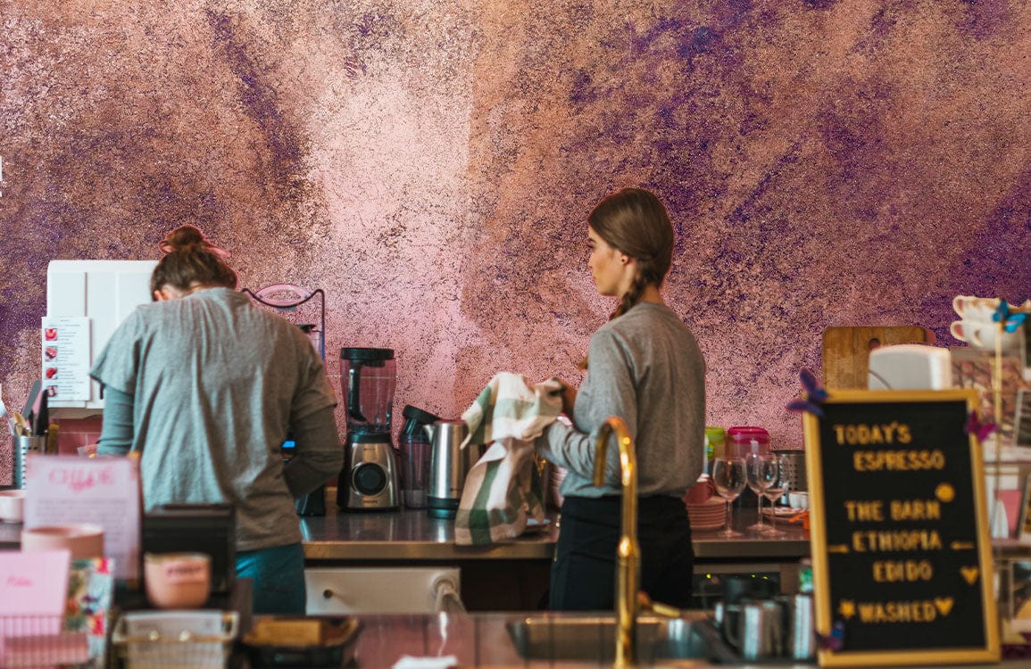 Deux baristas derrière un comptoir avec une murale mystérieuse pour papier peint panoramique