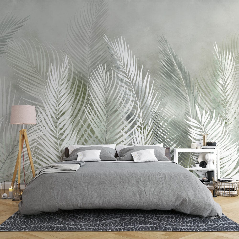 Image d’un lit avec duvet gris et oreillers blancs devant un papier peint mural à motif de plumes vertes