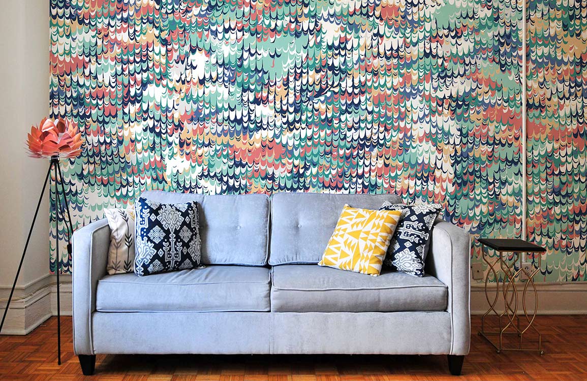 Canapé deux places gris clair avec coussins tuftés et coussins décoratifs, papier peint mural texture colorée