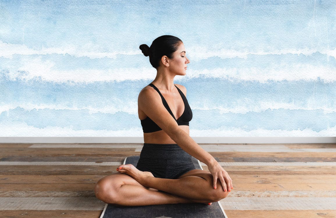 Femme en pose de yoga sur tapis sombre avec peinture murale vague aquarelle abstraite