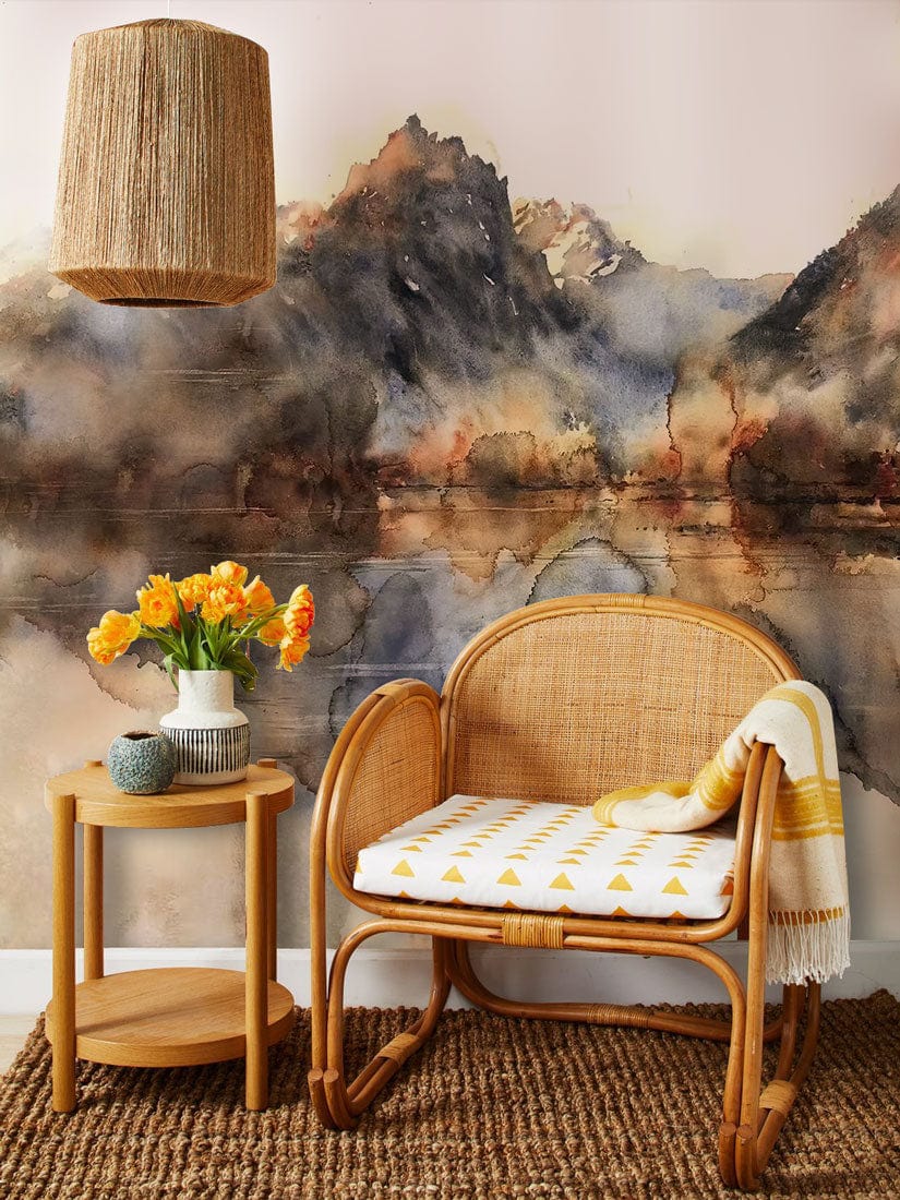 Chaise longue en rotin tissée avec coussin blanc à triangles jaunes, dans un décor mural aquarelle abstraite