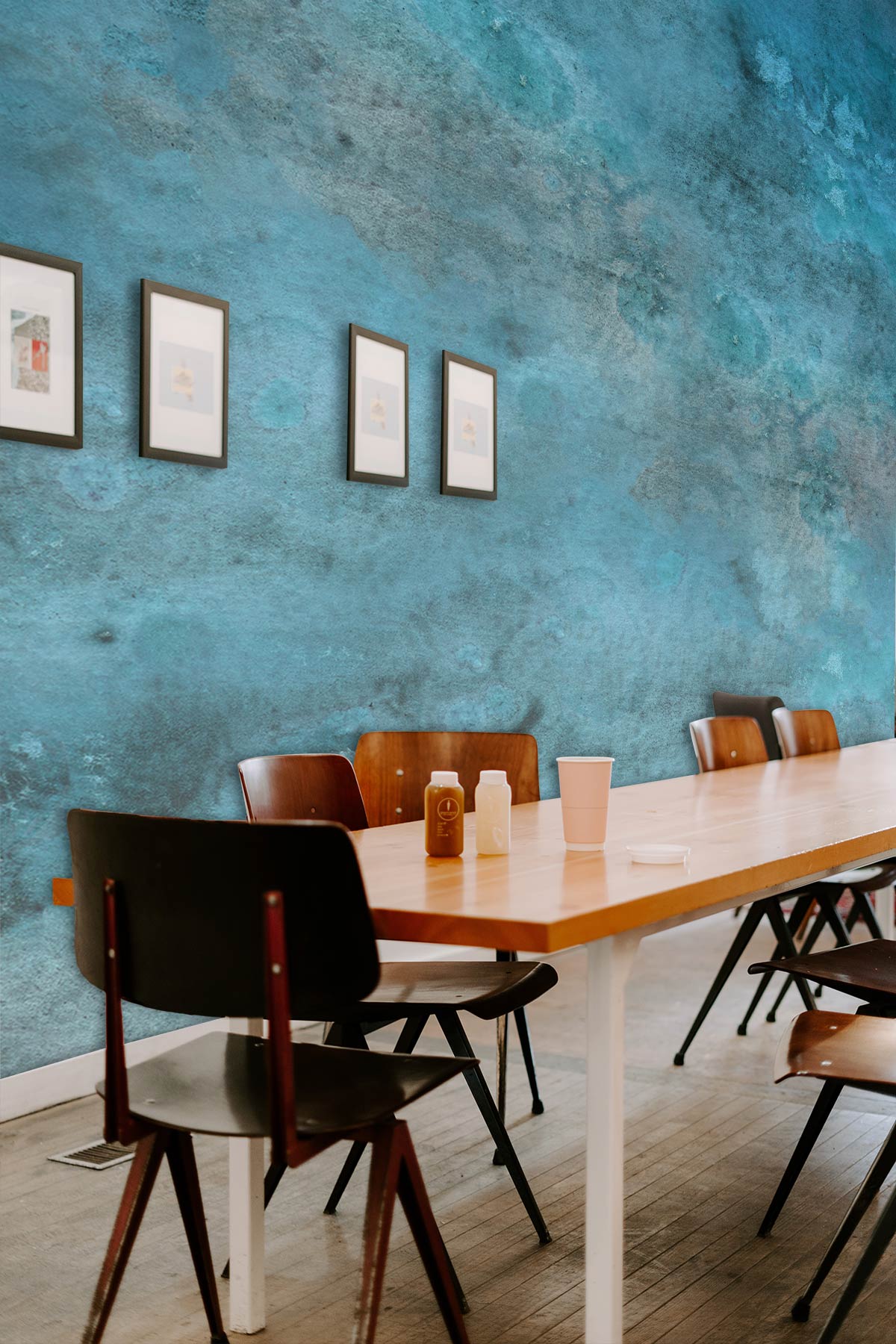 Table de conférence en bois avec chaises noires et brunes, mur bleu aquarelle