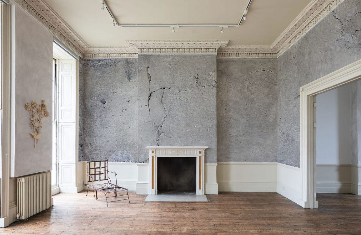 Papier peint mural blanc moucheté dans une pièce vide avec cheminée et murs gris texturés