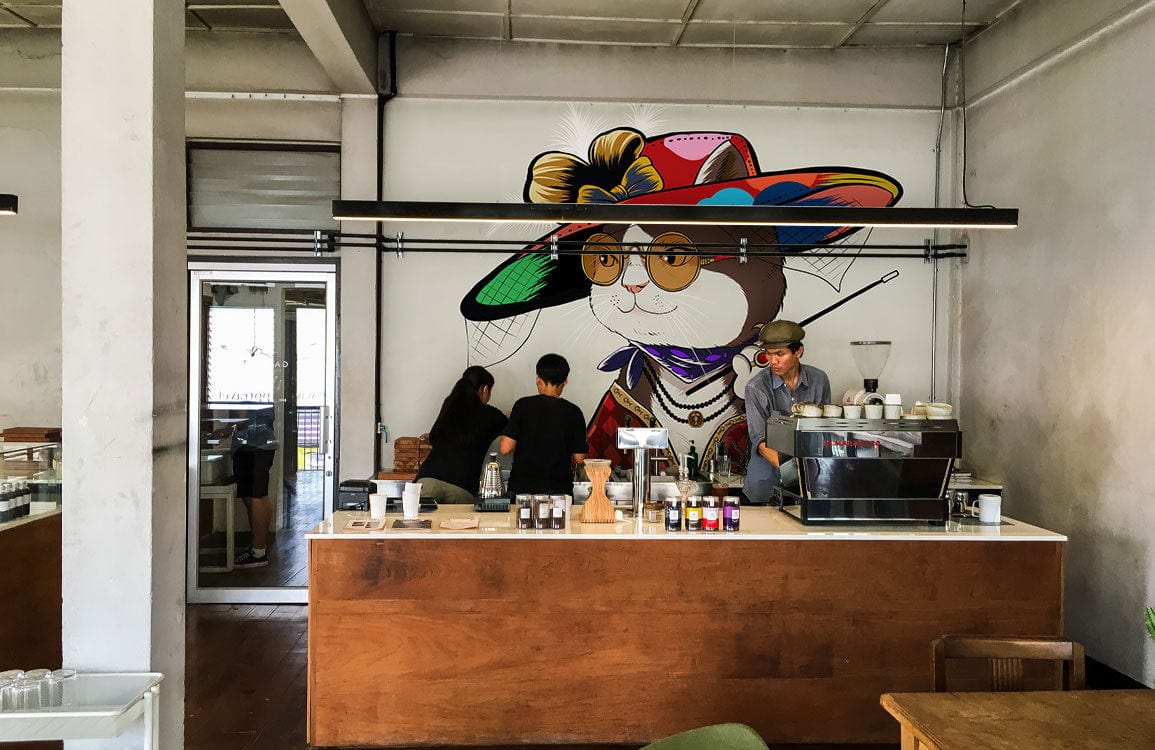 Peint mural dame chat coloré derrière le comptoir d’un café, papier peint mural élégant