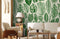Papier peint mural de feuilles tropicales vertes dans salon avec mobilier en bois naturel
