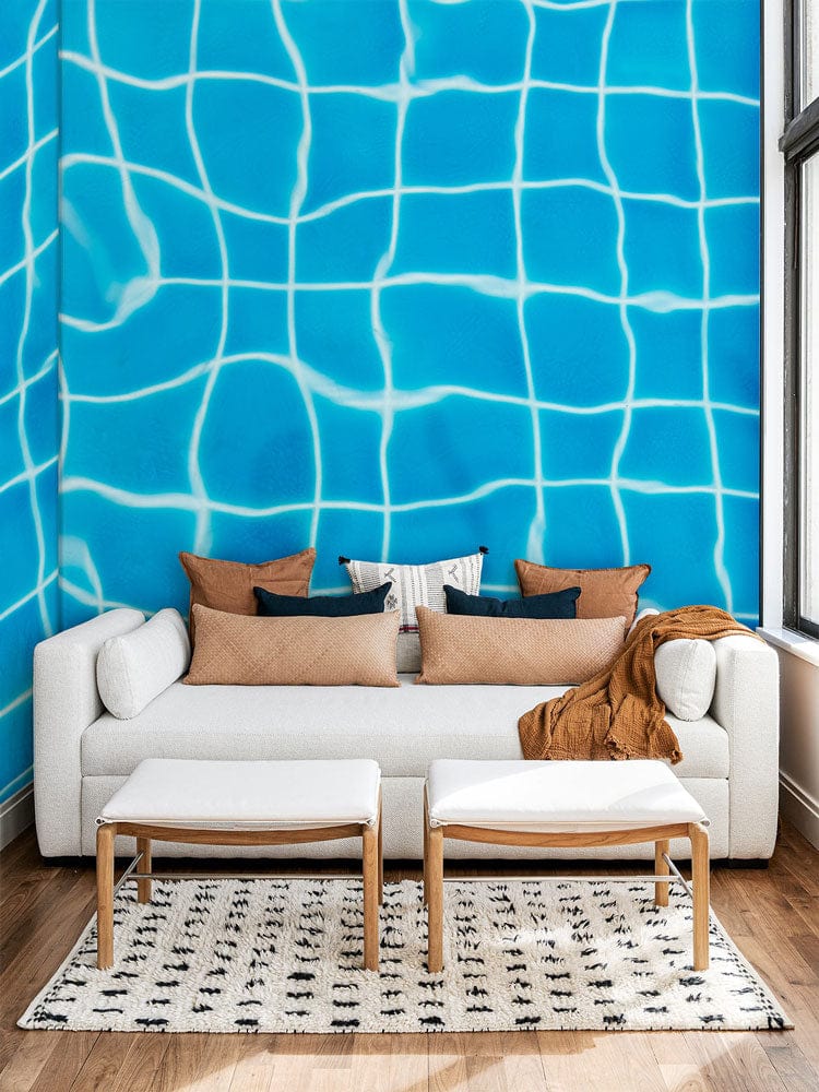 Image d’un lit de jour blanc avec coussins et couverture, décoré avec papier peint mural piscine claire