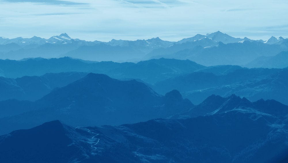 Papier peint mural des montagnes bleues brumeuses avec couches de montagnes bleues sous un ciel pâle