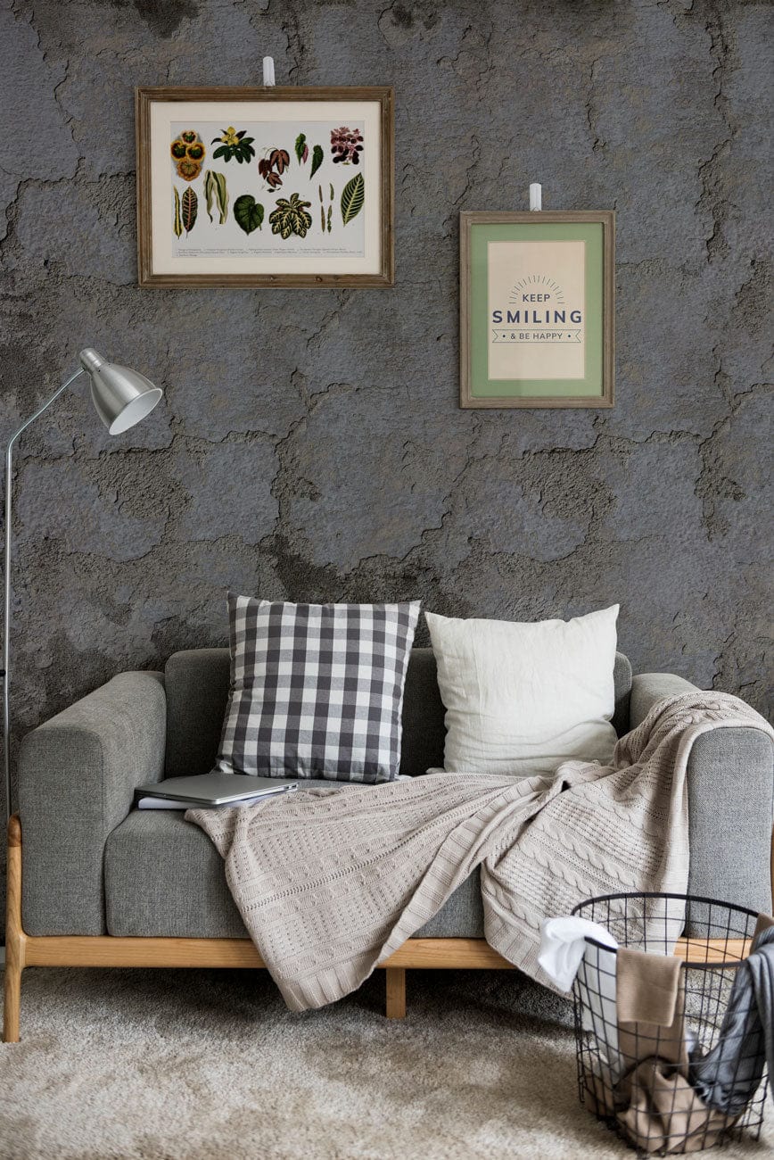 Canapé gris en tissu avec coussins et plaid, idéal pour un effet ciment mural écaillé