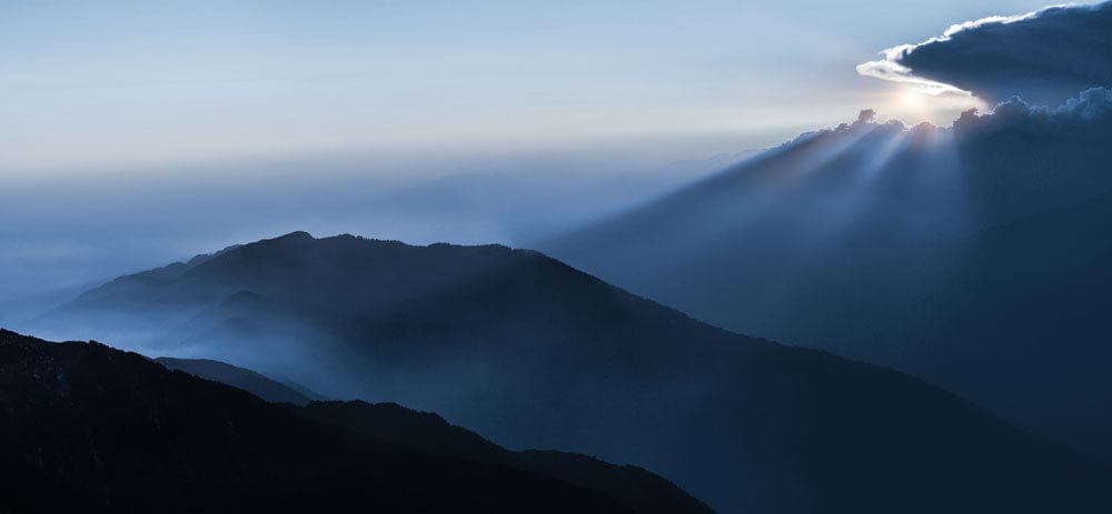 Papier peint mural Éparpillant de la lumière du soleil avec sommets de montagne brumeux