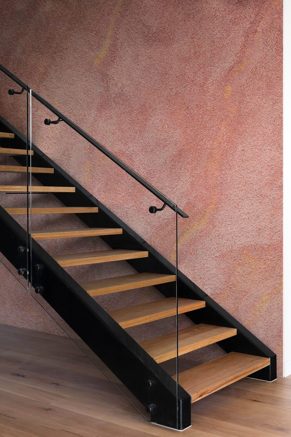 Escalier moderne avec treads en bois, balustrade en verre et mur imitation pierre