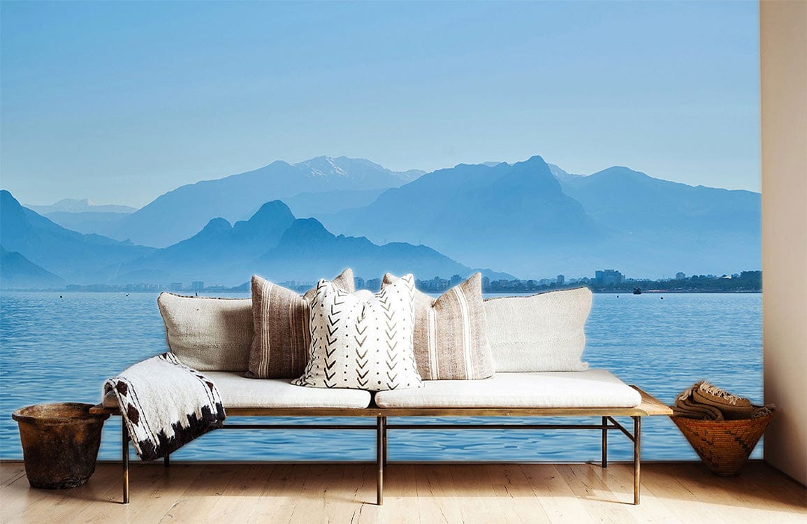 Banquette extérieure claire avec coussins décoratifs et plaid, dans le papier peint mural lac bleu