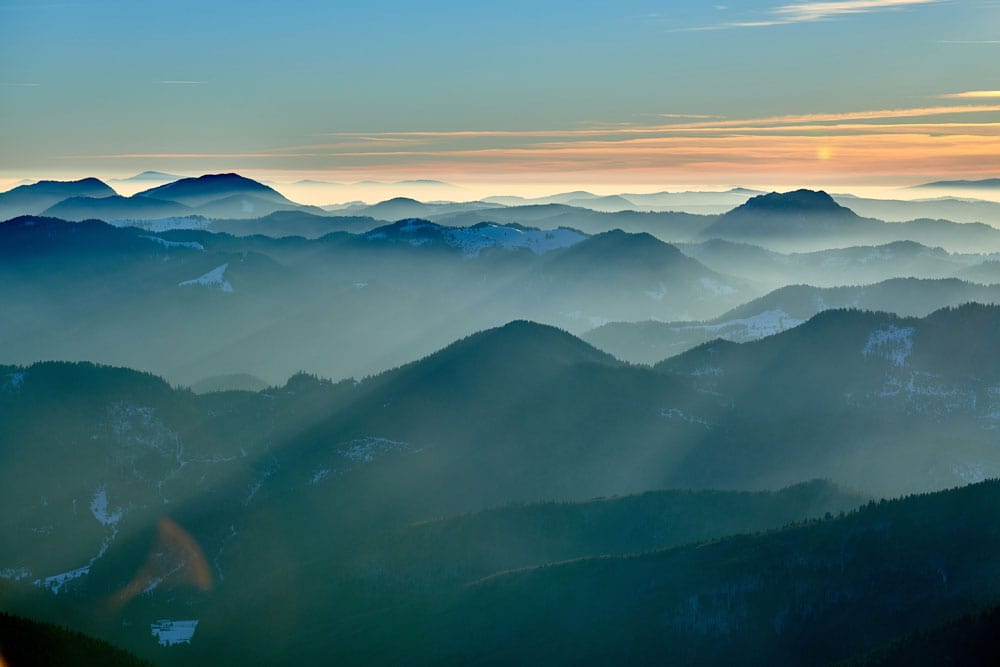 Papier peint mural montagnes avec vue sur une chaîne brumeuse au coucher du soleil