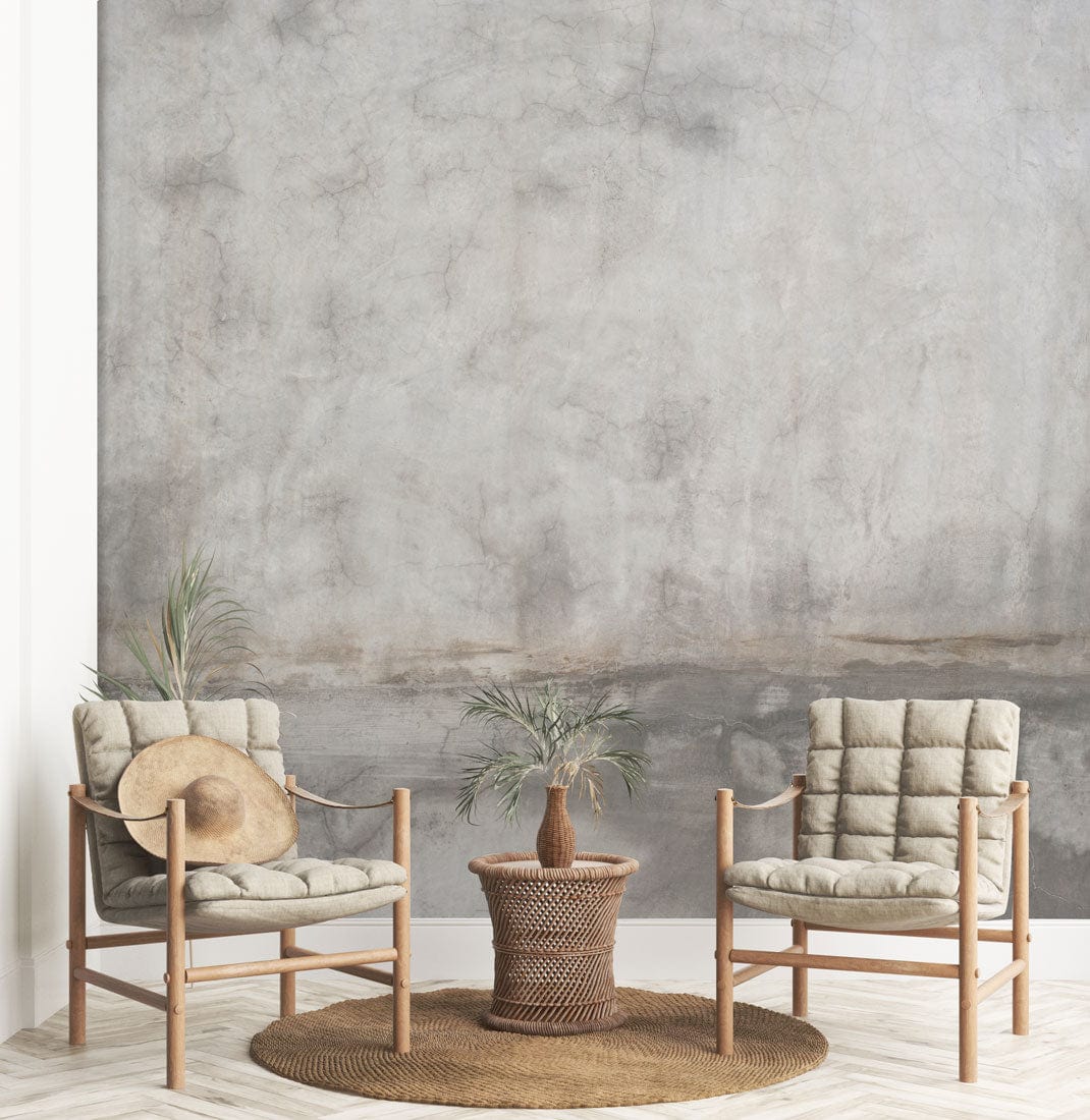Deux fauteuils en bois clair avec coussins sur tapis rond, mural ombre marbrée