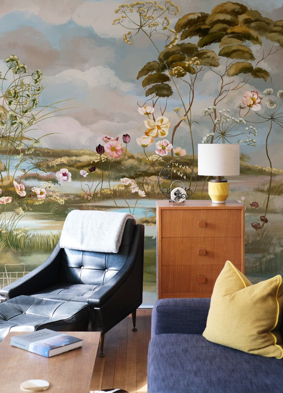Sofa bleu foncé avec coussin jaune, dans un décor de papier peint mural fleurs vintage