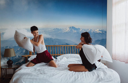 Deux femmes s’amusent lors d’une bataille d’oreillers sur un papier peint mural Vue sur les montagnes pour une évasion pittoresque
