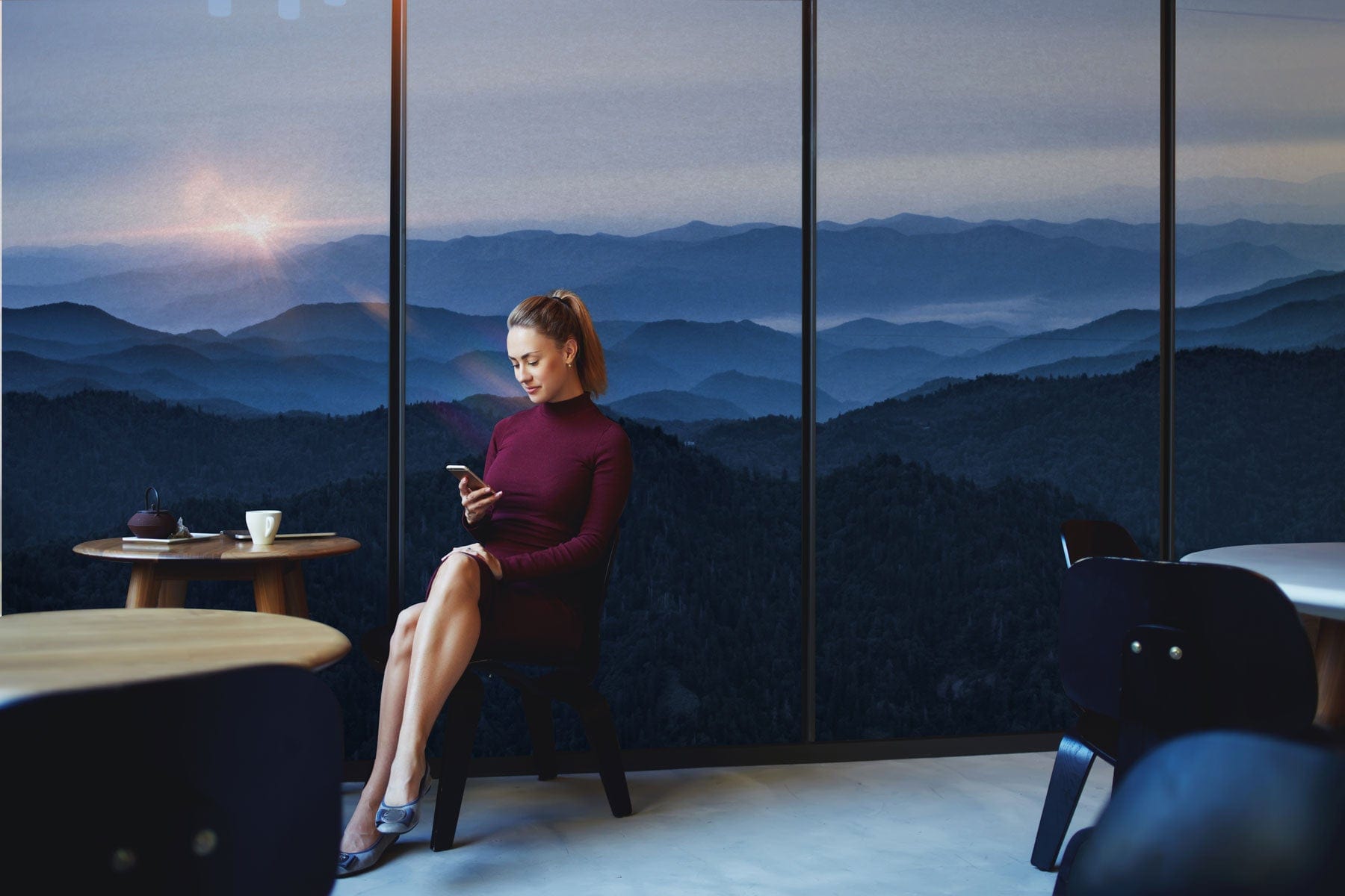 Femme en robe bordeaux dans un intérieur moderne avec vue montagne, papier peint panoramique