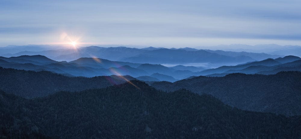 Papier peint panoramique montagnes au lever du soleil avec pics bleus et violets