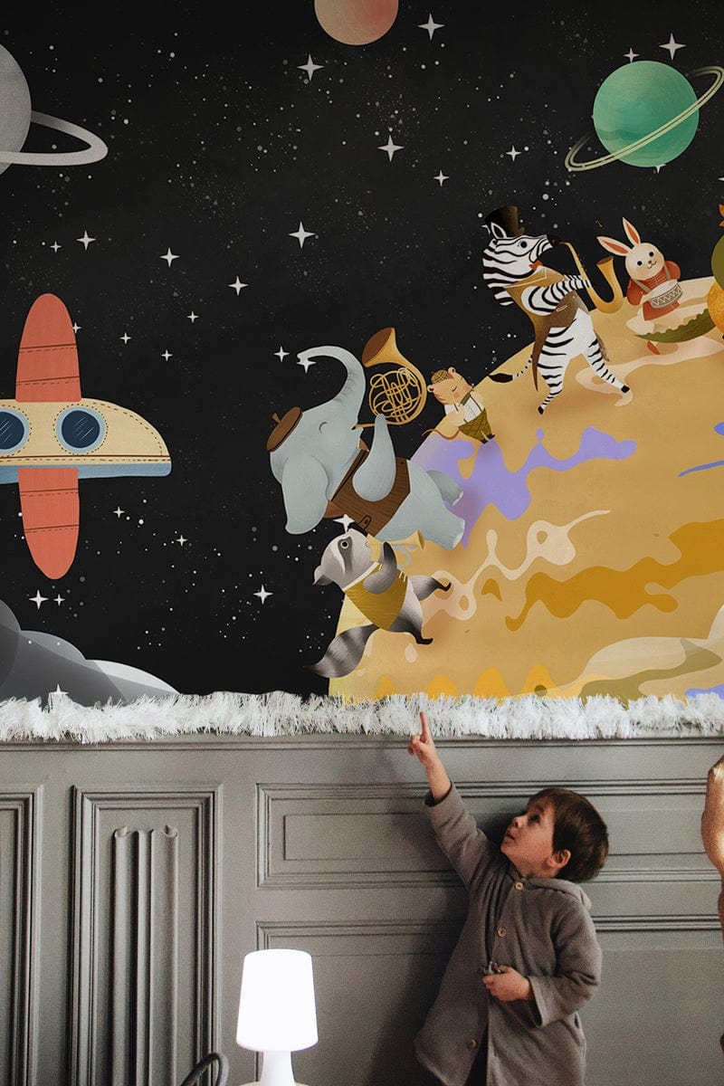 Enfant pointant vers une peinture murale du groupe d’animaux III avec thème spatial